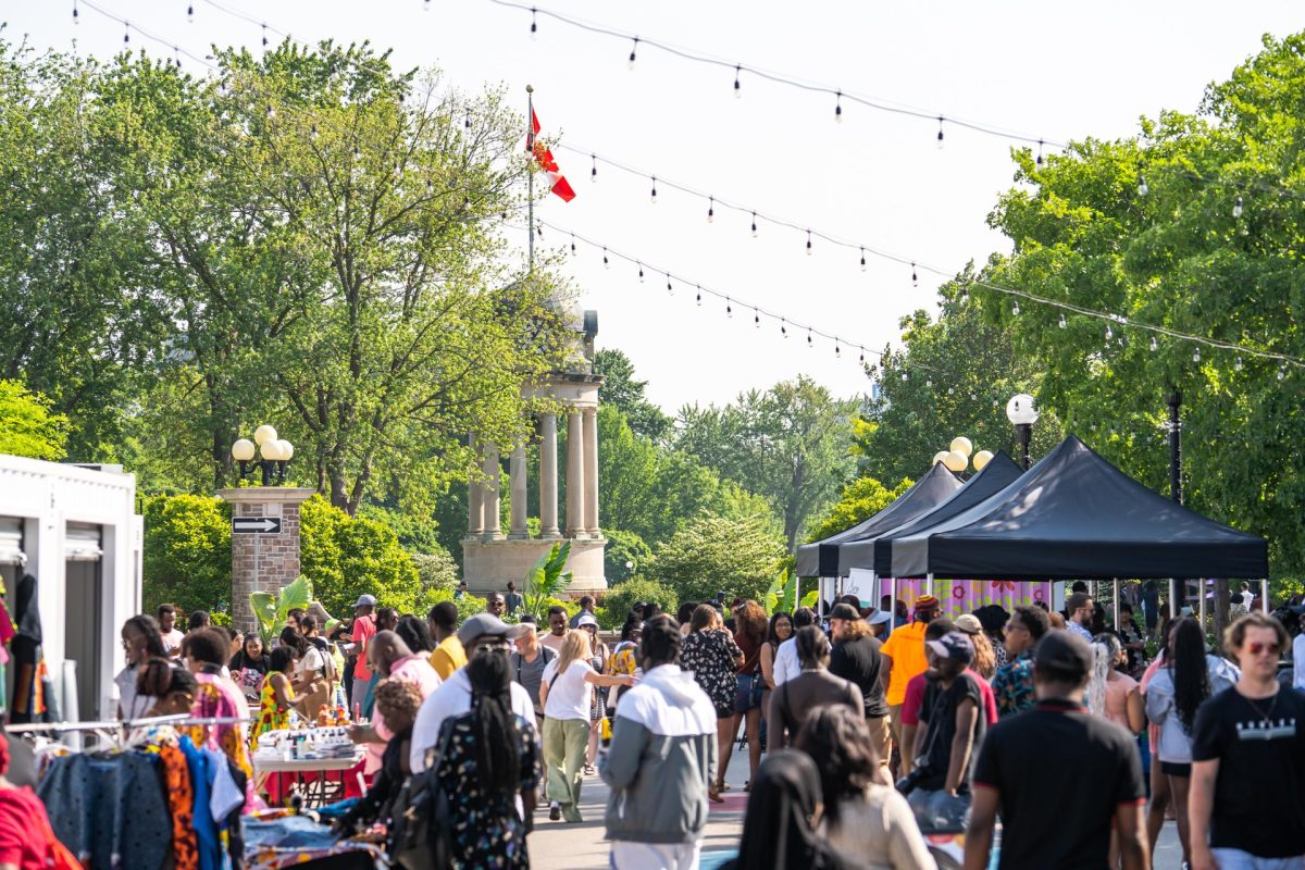 A large group of people walking through a festival in Kitchener's Victoria Park in the summer.