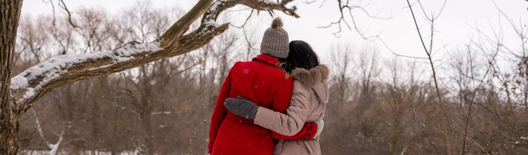 A couple hugging by the shore of the Conestogo River along the Health Valley Trail in the winter.