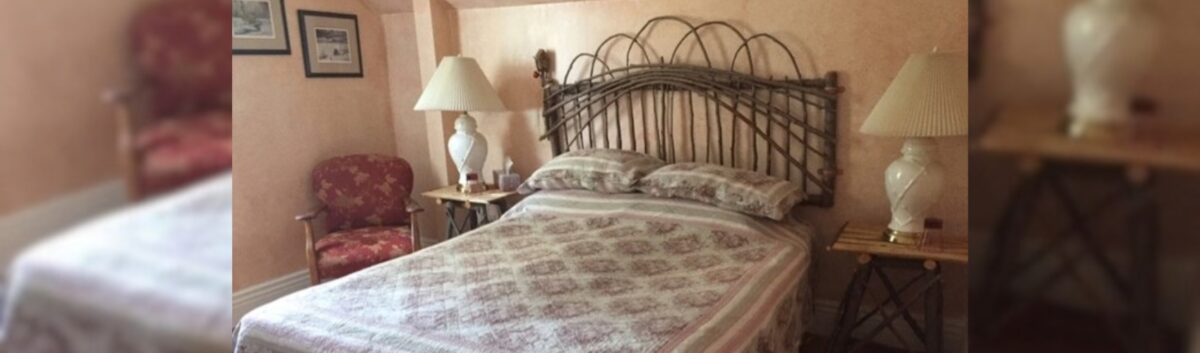 One of the cozy rooms at Baumann Haus Bed and Breakfast in St. Jacobs. There is a queen=-sized bed in the room that has a traditional looking quilt on it.