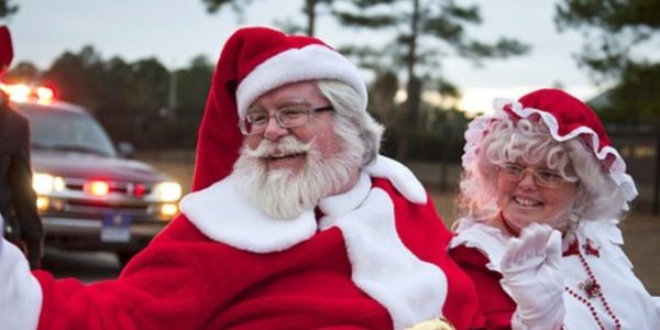 Santa and Mrs. Claus smiling and waving from a float at a local Santa Claus Parade.