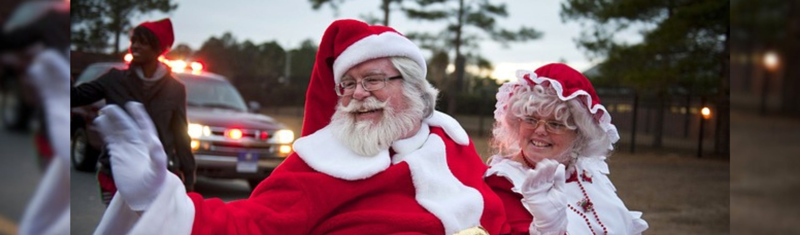 Santa and Mrs. Claus smiling and waving from a float at a local Santa Claus Parade.