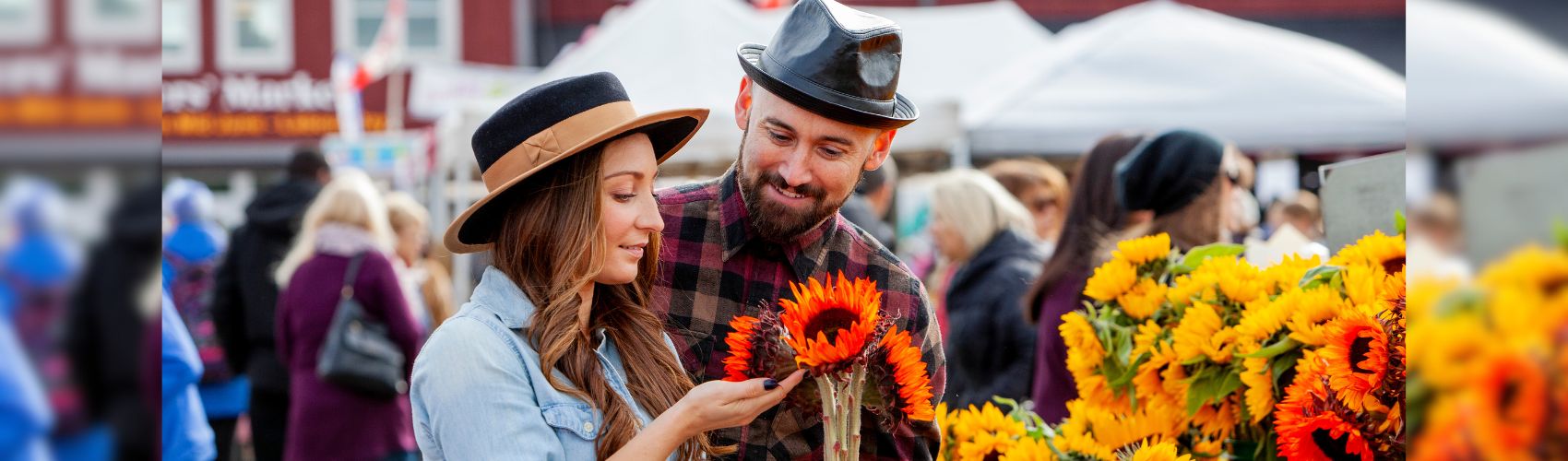Two people looking at bouquets of sunflowers at an outdoor stall at the St. Jacobs Farmers' Market