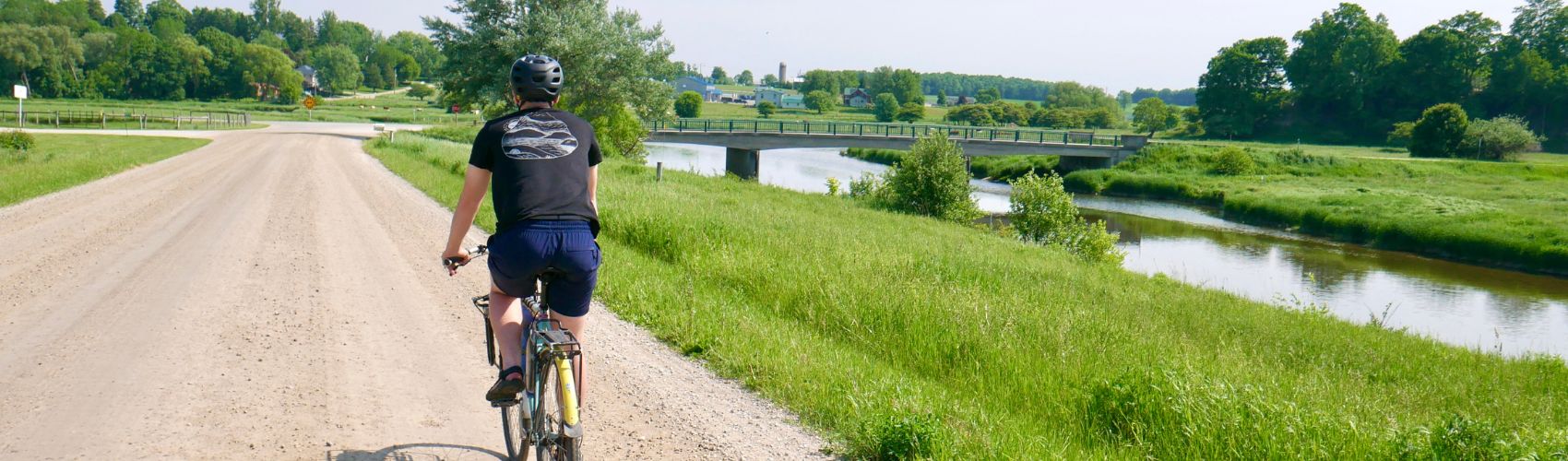 A cyclist riding along Temperence Road in Woolwich Township near St. Jacobs on a sunny summer's day. The gravel road runs along the Conestogo River.