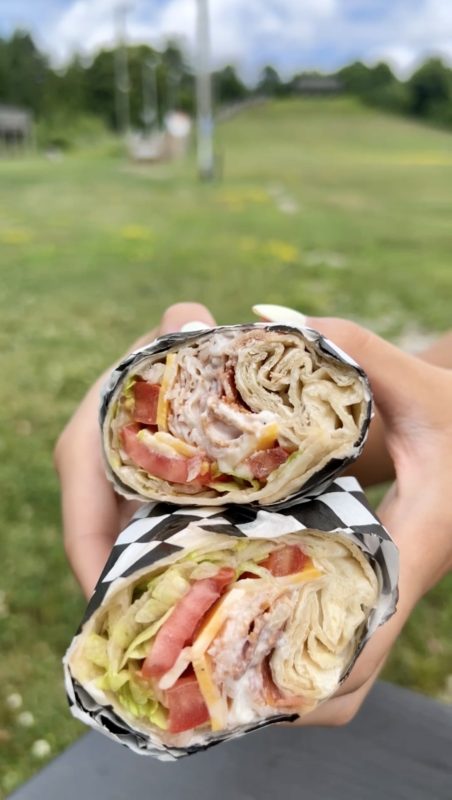 The filling of a larger wrap, cut in half, being held by someone.