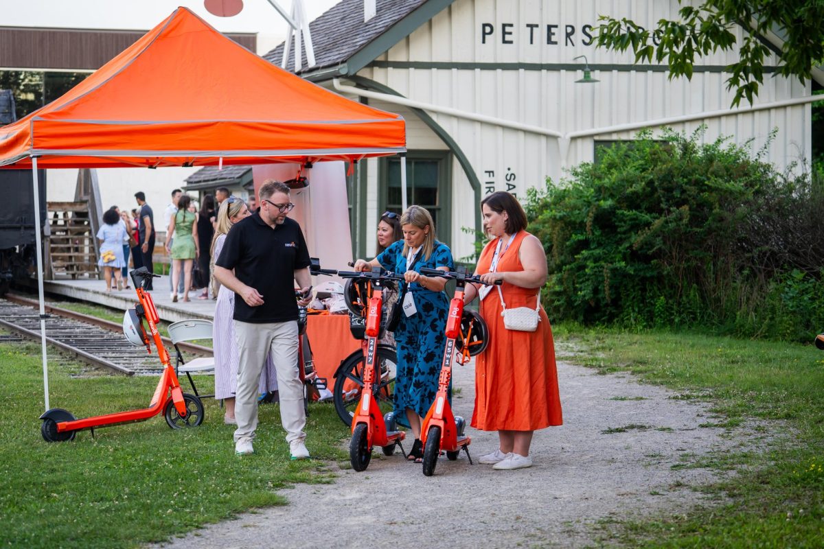 Three people trying out the Neuron Mobility electric scooters at the CSAE conference in Waterloo Region.