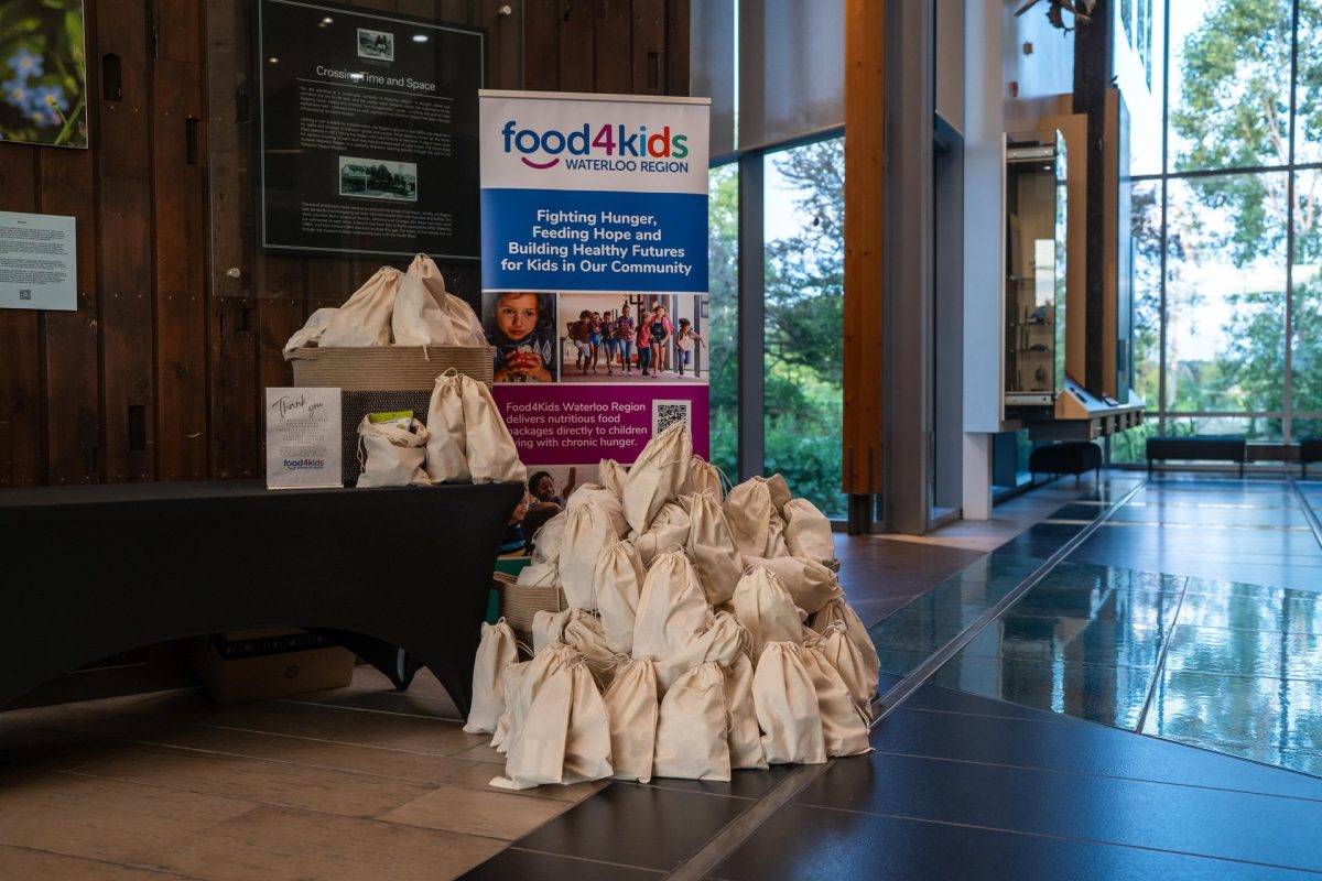 Bags of items to be donated to Food4Kids Waterloo Region on tables and arranged on the floor at the Waterloo Region Museum in Kitchener during the CSAE Summer Summit.