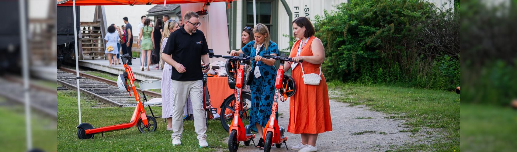 Three people trying out the Neuron Mobility electric scooters at the CSAE conference in Waterloo Region.