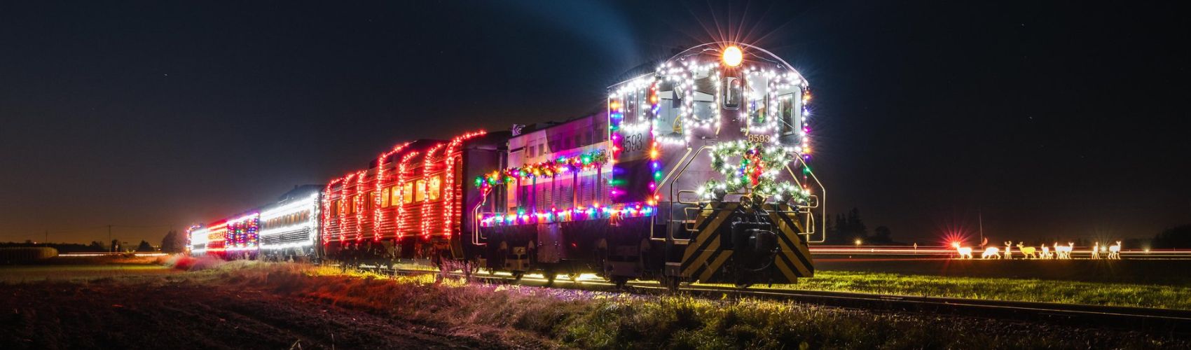 A Waterloo Central Railway holiday train all lit up and travelling along the tracks at night