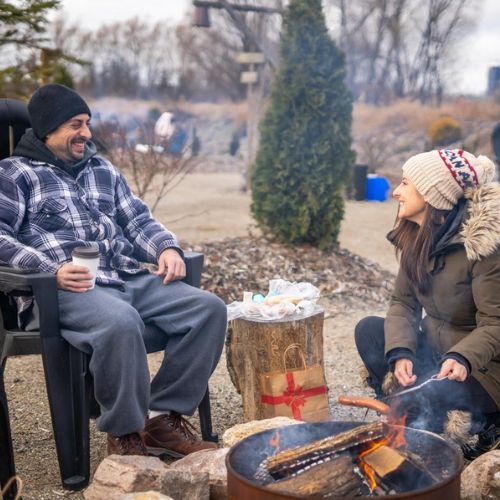 Two people sitting around a campfire and roasting s'mores at Snyder's Family Farm