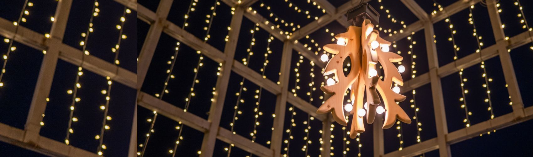 The large wooden mistletoe sculpture created by artist Sklyer Dietze, hanging in the Downtown Kitchener Light box. It is night, and both the light box and the mistletoe are lit up with white lights.