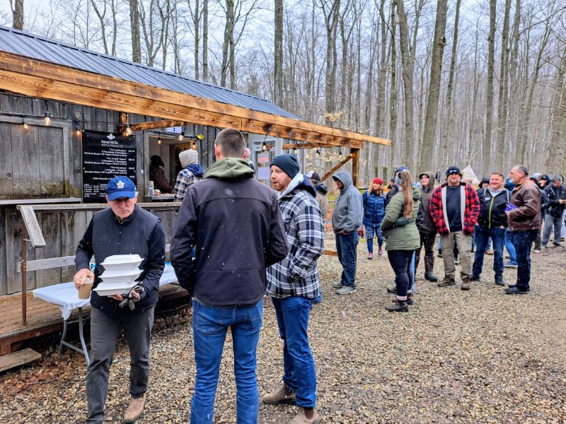 A line up of people waiting to participate in a pancake breakfast in Sand Hills Maple Products' sugar bush.