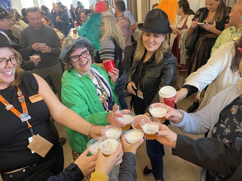 A group og travellers enjoying Oktoberfest in a festhalle in Waterloo Region. They have their beverage glasses all poised together as if they are cheering.