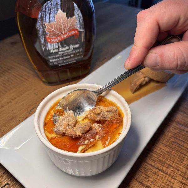 Maple Creme Brulee dessert at Borealis that is part of the Taste of Maple Trail in Waterloo Region. There is a bottle of local maple syrup behind the dessert.