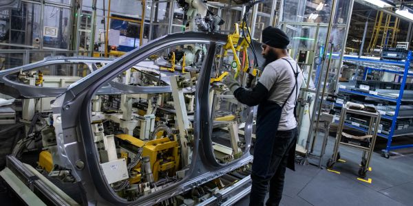 An assembly line worker adds a part to a car being assembled at the Toyota plant in Cambridge