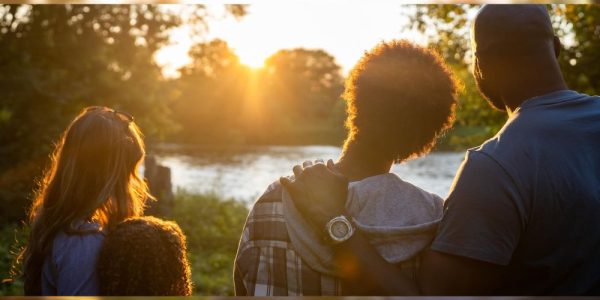 A family looking into the sun as it sets along the Grand River.