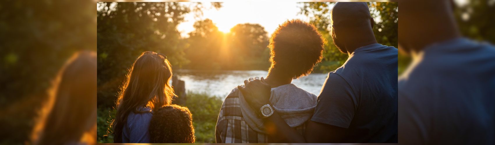 A family looking into the sun as it sets along the Grand River.