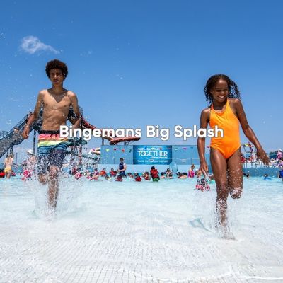 Two kids running through the shallow part of the wave pool at Bingemans Big Splash in Kitchener. It is a sunny summer's day, and there are lots of people enjoying the water part.