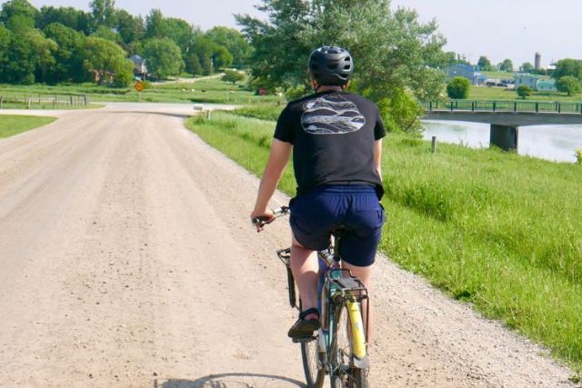 A cyclist riding along Temperence Road in Woolwich Township near St. Jacobs on a sunny summer's day. The gravel road runs along the Conestogo River.