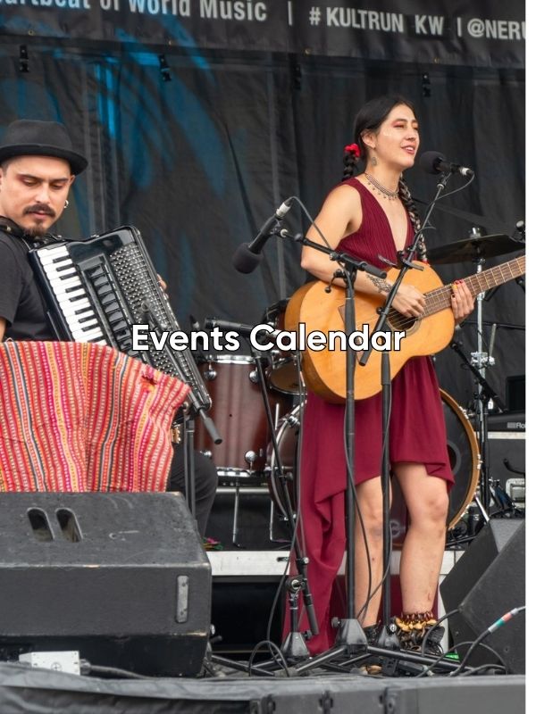 A singer and musician performing on an outdoor stage in the summer.