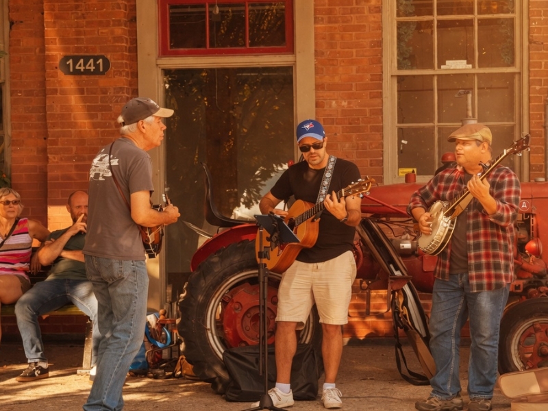 Three musicians performing in front of Eco Cafe in the villae of St. Jacobs during the Bales and Boots fall event.