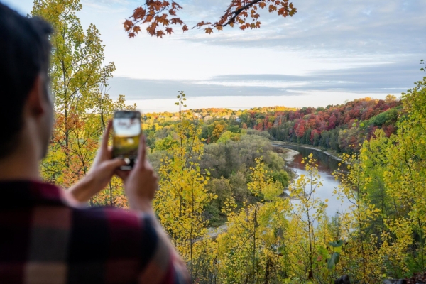 A person taking a picture of the fall colours on the trees from the Homer Watson lookout in Kitchener.