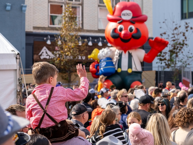 An intergenerational crowd taking in the festivities at Wilkommen Platz during the Thanksgiving Weekend. Many people are dressed in traditional Bavarian costumes.