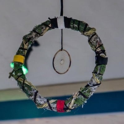 A circular Indigenous mistletoe creation that is made of cedar, sage and sweetgrass woven together, and bound together with thin leather strips. 