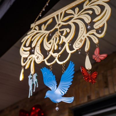 The gold laser cut mistletoe trail creation designed by artist Brianne Burnell. There are small images of birds, butterflies and deer suspended from the laser cut design.